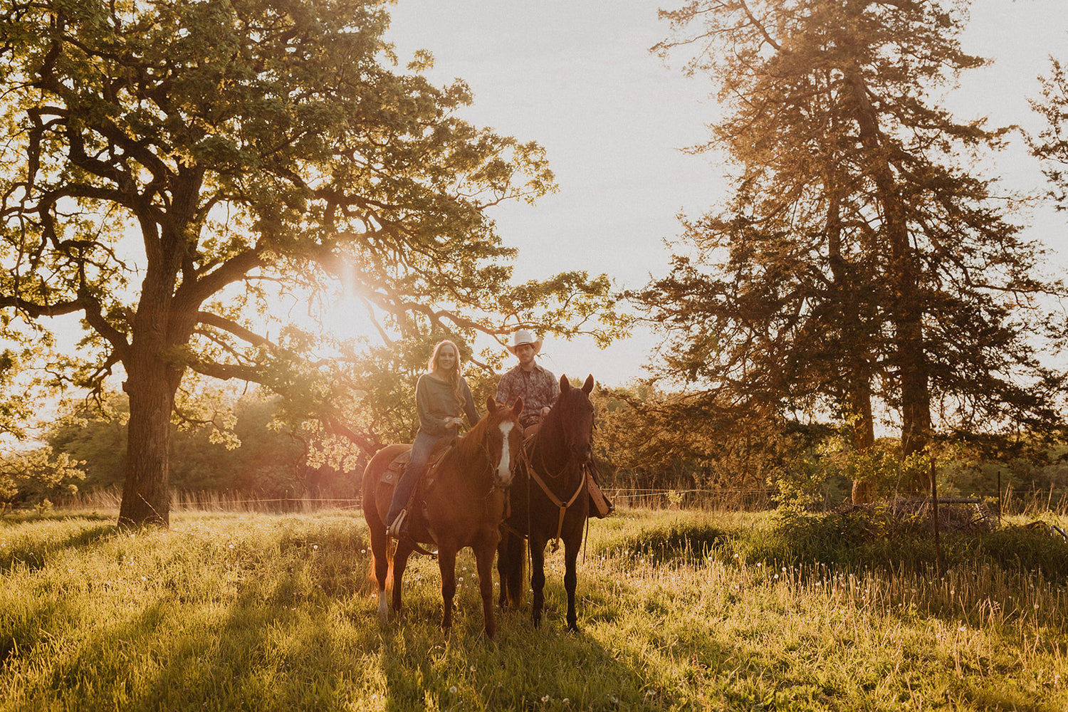 A man and a woman on horses with the sunset in the background 